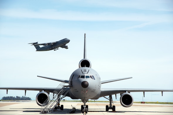 A KC-10 Extender is parked on the ramp as a C-5M Super Galaxy takes off at Travis Air Force Base, Calif., Mar. 16, 2017. (U.S. Air Force photo by Louis Briscese)