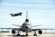 A KC-10 Extender is parked on the ramp as a C-5M Super Galaxy takes off at Travis Air Force Base, Calif., Mar. 16, 2017. (U.S. Air Force photo by Louis Briscese)