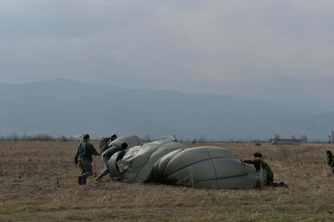 Ramstein Air Base Airmen and Bulgarian military service members assist in deflating a parachute at the drop zone during Exercise Thracian Spring 17 at Plovdiv Regional Airport, Bulgaria, March 15, 2017. Initial parachute deflation is important in order to prevent injury by the wind from further dragging landed paratroopers. The two-week combined training with Bulgaria’s military aims to facilitate overall relations and build their nations’ joint military capabilities. (U.S. Air Force photo by Staff Sgt. Nesha Humes)