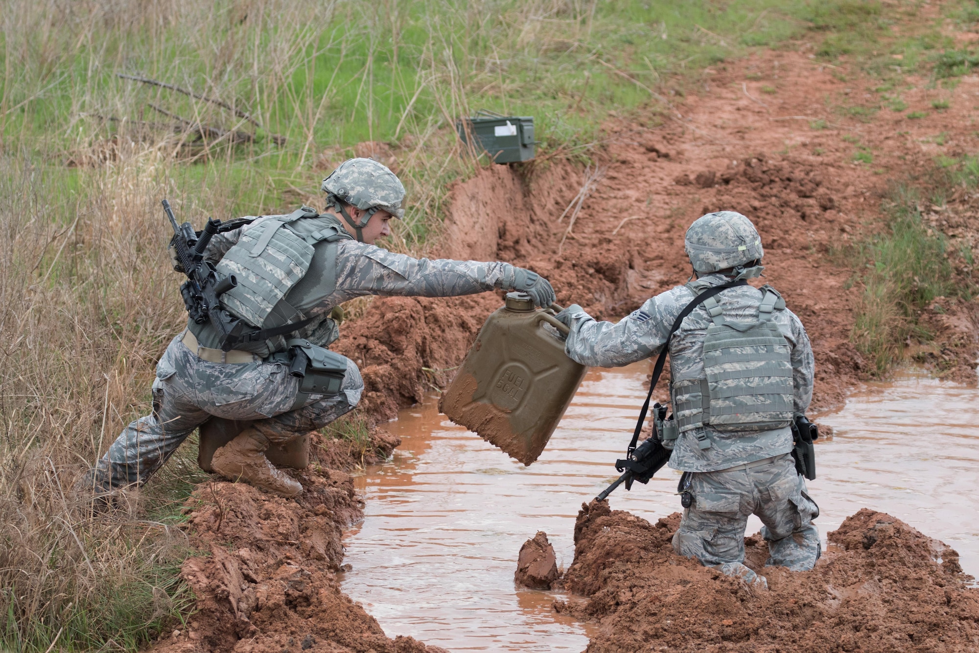 U.S. Air Force Staff Sgt. Robert Aldrich, left, 7th Security Forces Combat Arms Training and Maintenance instructor, works with Senior Airman Gustavo Vega, 7th SFS investigator, to complete the resupply challenge of the Top Defender Challenge March, 11, 2017, at Dyess Air Force Base, Texas. This event made teams work together to carry ammo cans and jugs of water through various terrains and obstacles. (U.S. Air Force Photo by Tricia Bruton)