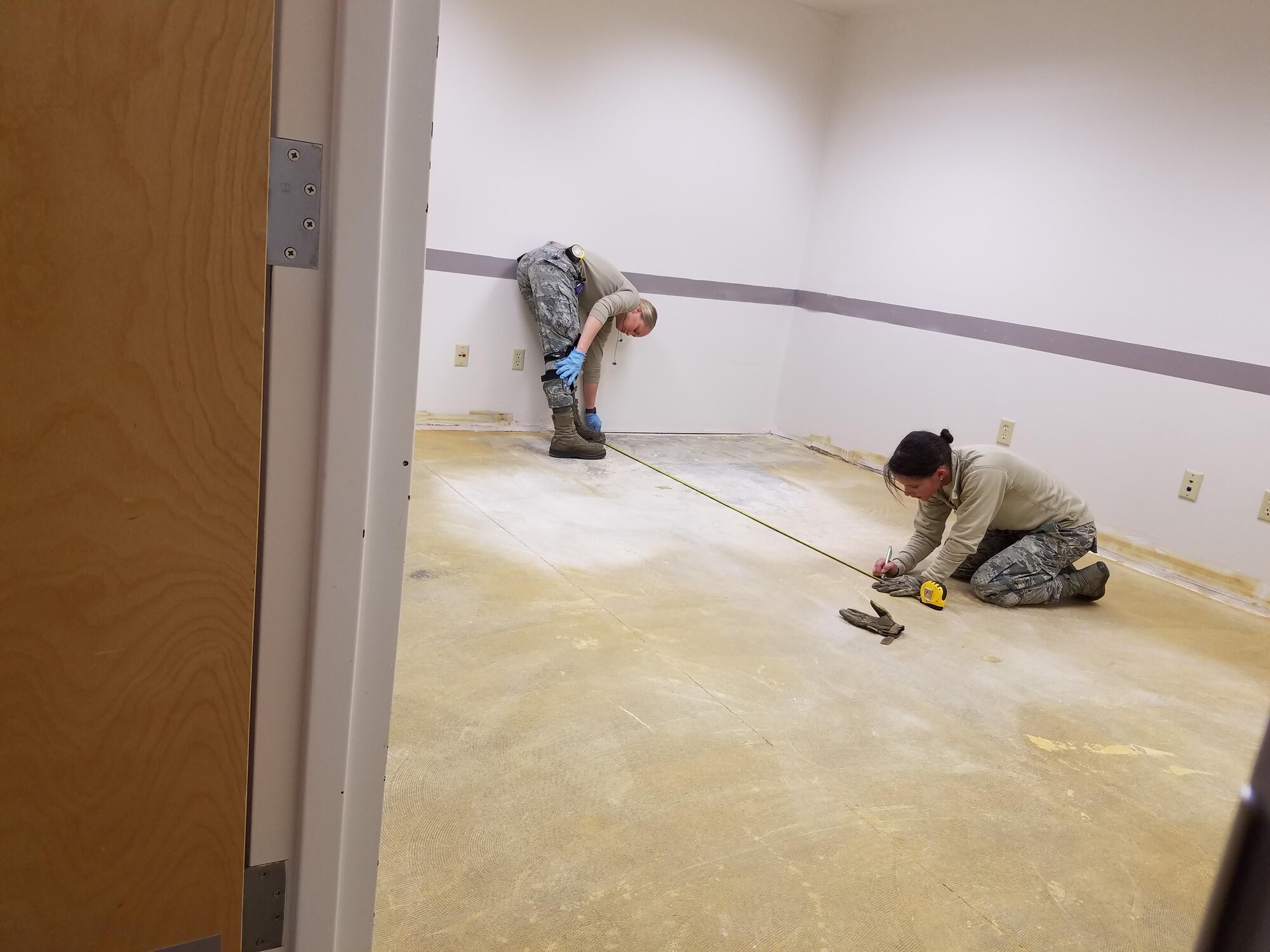 Senior Airman Jenna Fontaine and Senior Airman Sarah Young, both 92nd Civil Engineer Squadron structures technicians, measure for the center of the room as part of the starting point for laying the new carpet squares Dec. 12, 2016, at Fairchild Air Force Base, Wash. Airmen from the 92nd CES remodeled a building for the 92nd Operations Support Squadron to make way for the 384th Air Refueling Squadron moving here from McConnell Air Force Base, Kansas. (U.S. Air Force photo/Senior Airman Janelle Patiño/Released)