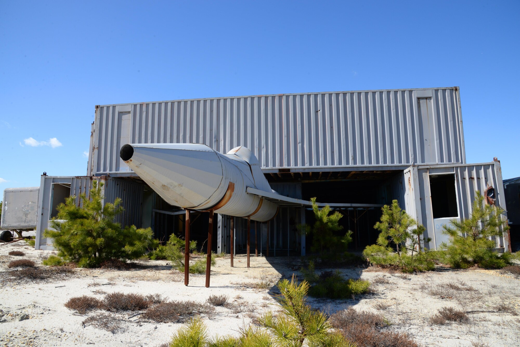 A picture of a sheet metal fabricated aircraft shape parked under a simulated hangar made of storage containers.