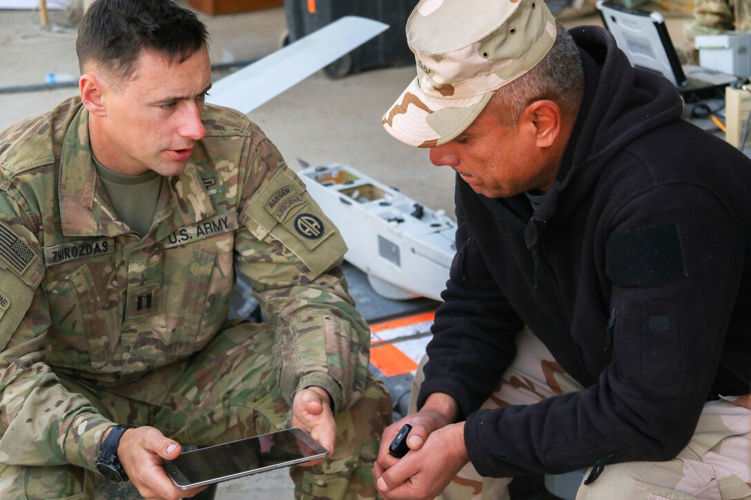 U.S. Army Capt. Mark G. Zwirzgdas, left, shares information acquired by his unit's Puma unmanned aerial vehicle flight with a 9th Iraqi army division leader near Al Tarab, Iraq, March 12, 2017. Zwirzgdas is assigned to the 82nd Airborne Division’s 2nd Brigade Combat Team, Combined Joint Task Force-Operation Inherent Resolve. Army photo by Staff Sgt. Jason Hull 