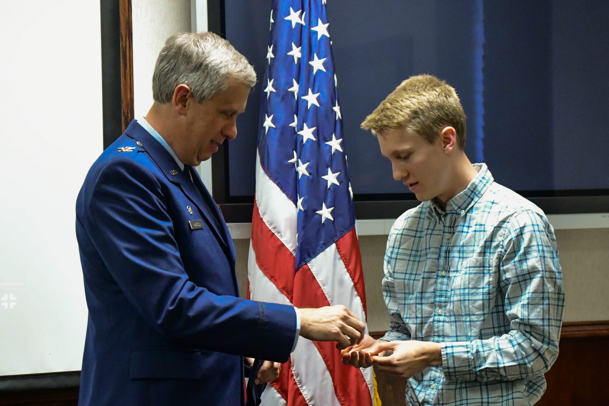 Col. Robert Burgess, commander of the 307th Operations Group, Barksdale Air Force Base, La., presents his son, Adam Burgess, a second lieutenant coin during a commissioning ceremony on Barksdale March 15, 2017. Adam is commissioning into the Air Force and plans to serve as a doctor. (U.S. Air Force photo by Master Sgt. Dachelle L. Melville/Released)   