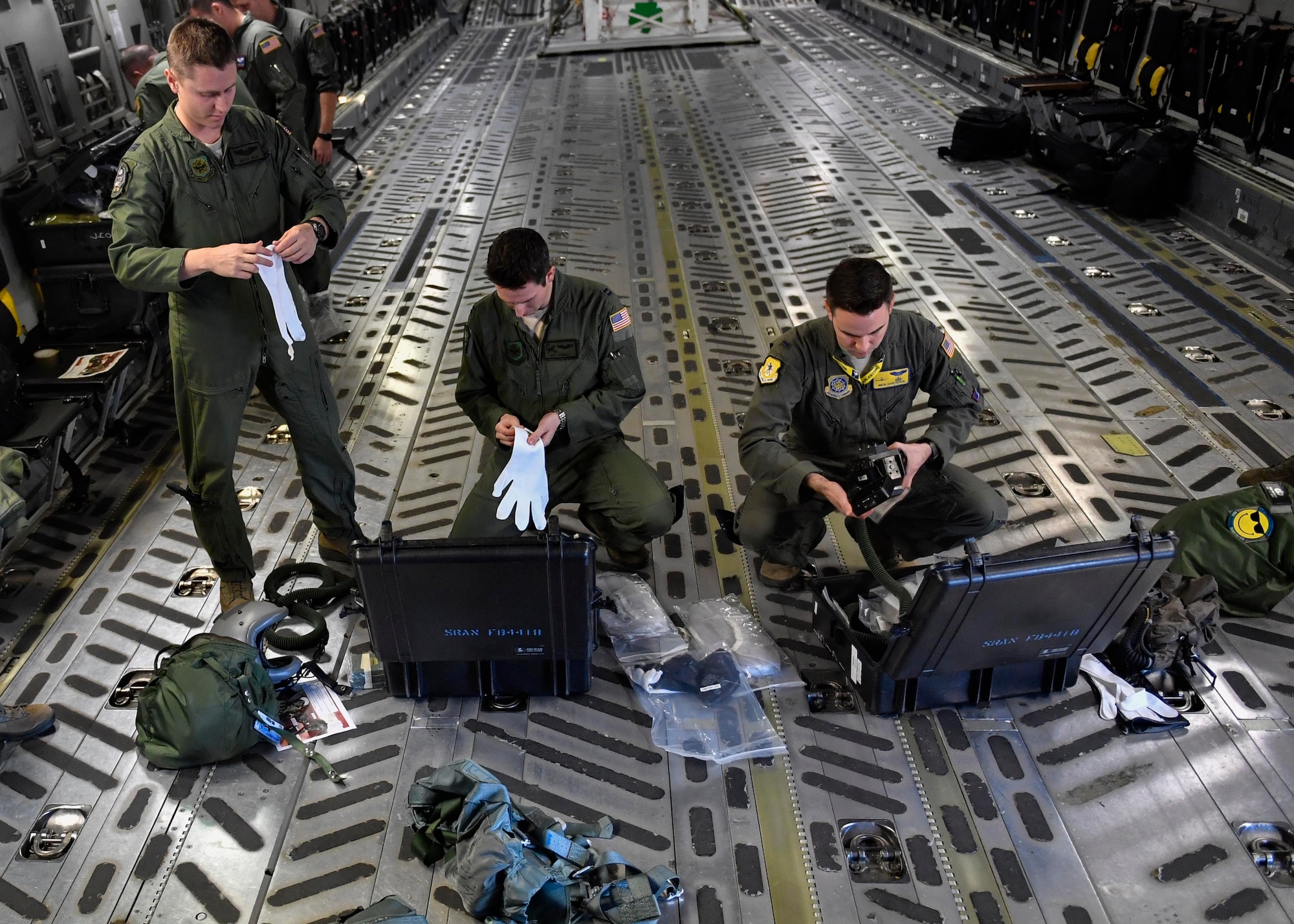Capt. Bryce Weir, left, 15th Airlift Squadron pilot, Capt. Jason Carroll, center, 15th AS airdrop instructor pilot, and 2nd Lt. Nick Hartsock, 15th Airlift Squadron pilot, open their aircrew eye and respiratory protection system (AERPS) kits before a flight to North Auxiliary Airfield in North, South Carolina, March 15, 2017 to execute in-flight training with (AERPS) equipment. The flight marked the first time in more than 10 years where aircrews wore AERPS equipment. AERPS equipment consists of a rubber mask, multiple layers of boots and gloves, fan filter system and an audio and speaker system.