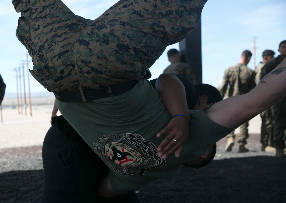 The wife of a Marine with 3rd Battalion, 4th Marines, 7th Marine Regiment, hip-tosses her husband during the Marine Corps Martial Arts Program instruction at Del Valle Field during the battalion’s Jane Wayne Day aboard Marine Corps Air Ground Combat Center, Twentynine Palms, Calif., March 8, 2017. (U.S. Marine Corps photo by Cpl. Julio McGraw)