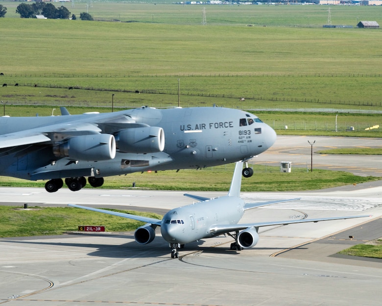 A Boeing KC-46A Pegasus arrives at Travis Air Force Base, Calif. while as C-17 Globemaster III takes off, Mar. 7, 2017. Travis was selected as a preferred location for the Air Force's newest refueling aircraft in January. This is the first time the aircraft has flown at an Air Mobility Command base and is scheduled to complete ground and flight testing during its time at Travis. (U.S. Air Force photo by Louis Briscese) 