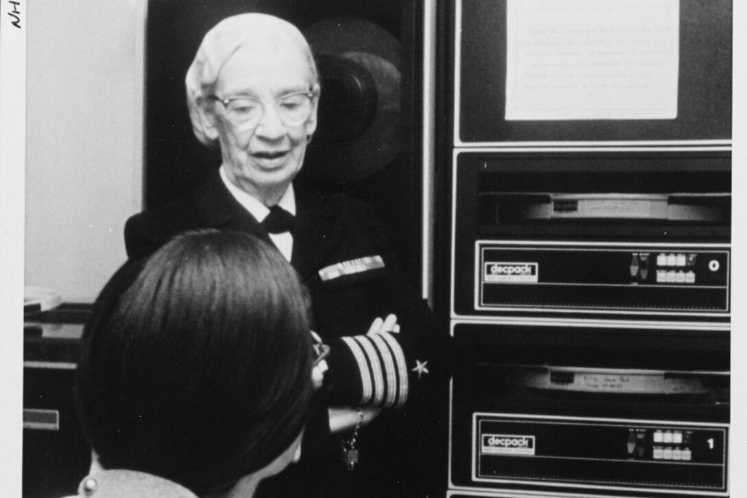 Capt. Grace Hopper, head of the Navy Programming Language Section of the Office of the Chief of Naval Operations, discusses her work with a staff member, August 1976. Navy photo by David C. MacLean