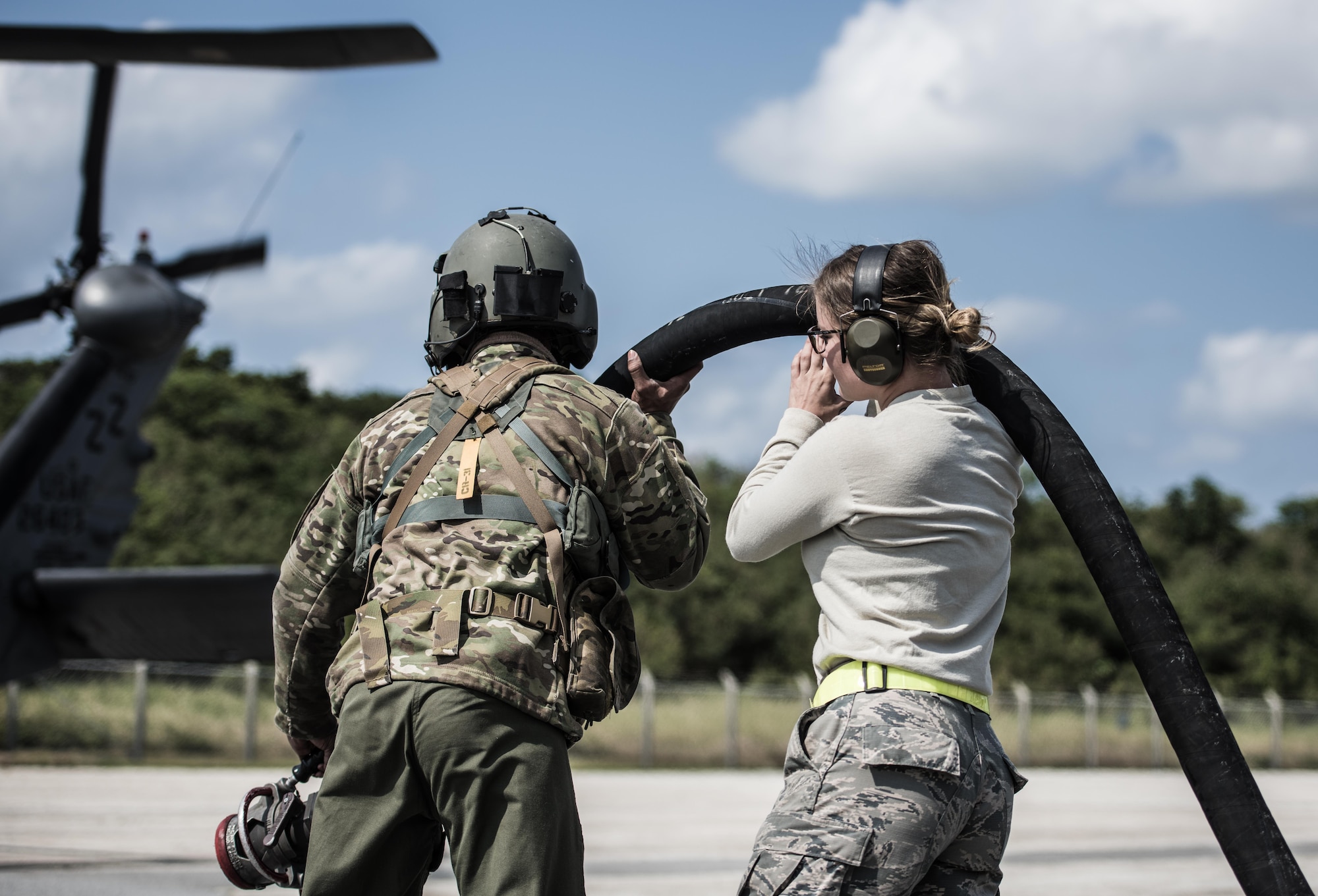 Airmen from the 33rd Rescue Squadron and the 18th Logistics Readiness Squadron lift a fuel hose to refuel an HH-60 Pavehawk during routine training on the flightline March 7, 2017, at Kadena Air Base, Japan. Aircrews rely on fuel from the 18th LRS to keep aircraft running and ready. (U.S. Air Force photo by Senior Airman Omari Bernard)