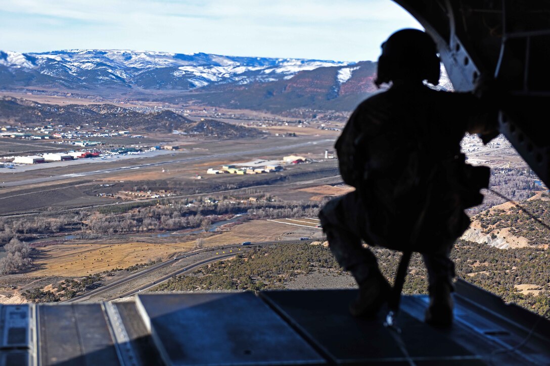 A South Carolina Army National Guard crew chief looks out the back ramp of a CH-47F Chinook helicopter for proper clearance while conducting high-altitude flight operations near Vail, Colo., March 10, 2017. Army National Guard photo by Staff Sgt. Roberto Di Giovine 