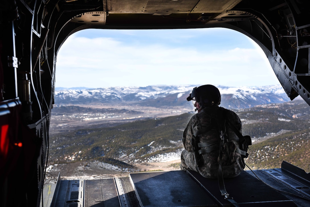 A South Carolina Army National Guard crew chief looks out the back ramp of a CH-47F Chinook helicopter at the Colorado mountains while conducting high-altitude flight operations near Vail, Colo., March 10, 2017. Army National Guard photo by Staff Sgt. Roberto Di Giovine
