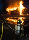 A 35th Civil Engineer Squadron firefighter monitors the fire during a controlled burn of a condemned building at Misawa Air Base, Japan, March 15, 2017. To ensure the fire was contained the firefighters sprayed surrounding trees and grassy areas with water. The firefighters trained on their forcible entry techniques and learned more about fire behavior. This training furthered their preparedness to respond to an emergency and ensure the mission doesn’t fail. (U.S. Air Force photo by Staff Sgt. Melanie A. Hutto)