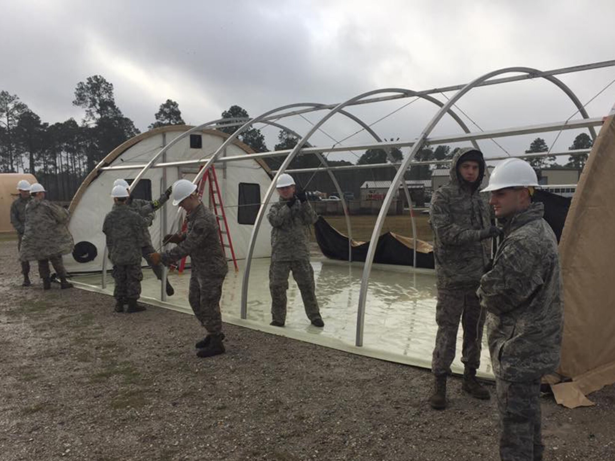 Under the supervision of a training cadre, emergency management personnel work with fire department personnel to erect a small shelter system during an exercise at Tyndall Air Force Base, Florida, January 22, 2017. The exercise was part of Silver Flag, a mandatory weeklong training exercise for certain civil engineer specialties in the military. (U.S. Air Force courtesy photo)
