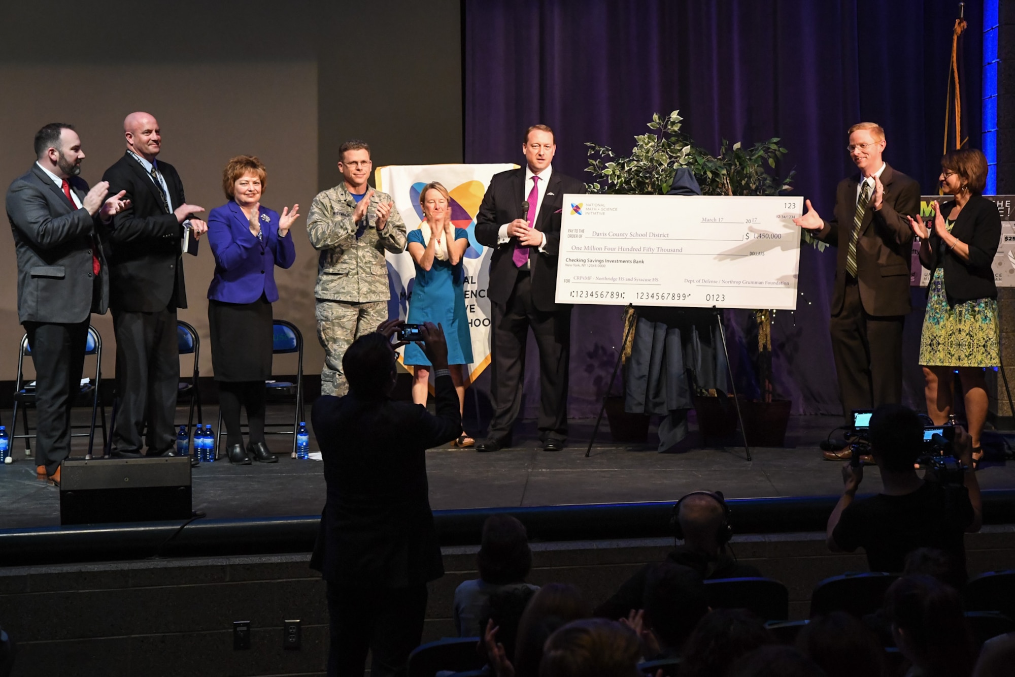 Officials from Hill Air Force Base, the Northrup Grumman Foundation, and the National Math + Science Initiative applaud after presenting multiple checks totaling $1.7 million for STEM education in the Davis School District during an event held at Syracuse High School, Utah, March 17, 2017. The majority of the investment will fund participation in the NMSI College Readiness Program at Northridge and Syracuse High Schools. The Department of Defense contributed $1.2 million, Northrup Grumman donated $250,000 and Hill AFB invested an additional $250,000 in partnership with the State of Utah STEM Action Center. (U.S. Air Force photo/ R. Nial Bradshaw)