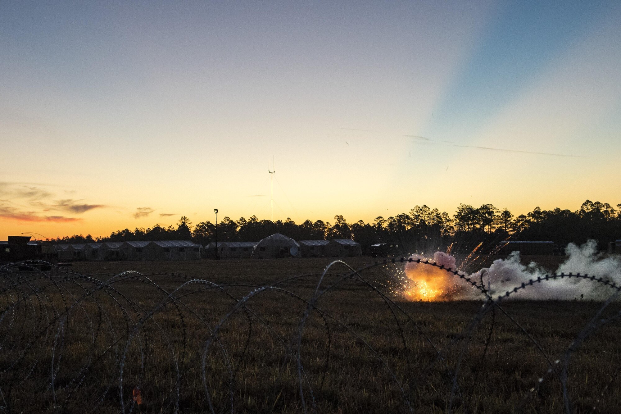 A ground burst simulator explodes near a simulated austere base during a Mission Readiness Exercise, March 11, 2017, at Avon Park Air Force Range, Fla. The MRX took place March 2-13 and ensured the 822d Base Defense Squadron could efficiently deploy anywhere in the world in less than 72 hours. The MRX took place March 2-13 and ensured the 822d BDS could efficiently deploy anywhere in the world in less than 72 hours. During the two week MRX, the squadron was evaluated on its ability to set-up a bare base, effectively thwart enemy attacks, run a secure Tactical Operation Center and maintain positive relationships with villagers in surrounding areas. (U.S. Air Force Photo by Airman 1st Class Janiqua P. Robinson)