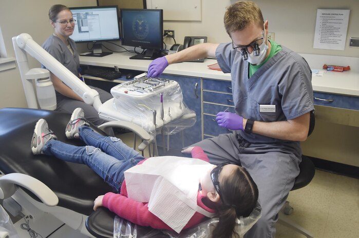 Lt. Col. Nathan Schwamburger, right, 628th Aerospace Medicine Squadron dental flight commander, and Staff Sgt. Kayla Ferguson, left, 628th AMDS dental assistant, perform a dental exam for Olivia King, center, 3 year old daughter of Maj. Scott King, 628th Medical Group bioenvironmental engineering flight commander, during the annual Give Kids A Smile campaign at Joint Base Charleston, South Carolina, March 17. The event offered free dental including dental exams, prophylaxis, sealants if needed, fluoride treatment and education to children ages two to 12 years old. (U.S. Air Force photo by Staff Sgt. Christopher Hubenthal)