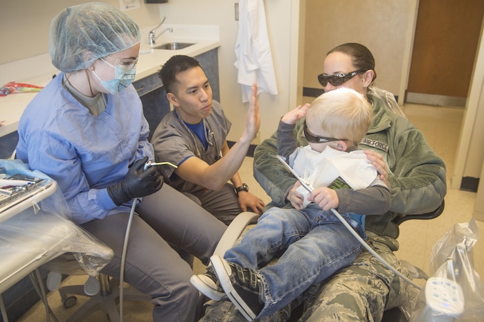Capt. Jeffrey Yee, middle left, 628th Aerospace Medicine Squadron general dentist, and Senior Airman Jasmina Gantt, left, 628th AMDS oral preventative assistant, congratulate Decklan Gibbs, foreground right, 2 year old son of Airman 1st Class Holly Gibbs, background right, 437th Aerial Port Squadron air cargo services, for completing a dental exam during the annual Give Kids A Smile campaign at Joint Base Charleston, South Carolina, March 17. The event offered free dental including dental exams, prophylaxis, sealants if needed, fluoride treatment and education to children ages two to 12 years old. (U.S. Air Force photo by Staff Sgt. Christopher Hubenthal)