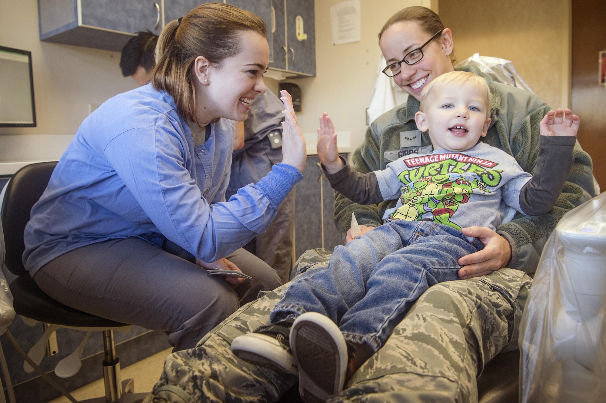 Senior Airman Jasmina Gantt, left, 628th Aerospace Medicine Squadron oral preventative assistant, completes a dental examination for Decklan Gibbs, foreground right, 2 year old son of Airman 1st Class Holly Gibbs, background right, 437th Aerial Port Squadron, during the annual Give Kids A Smile campaign at Joint Base Charleston, South Carolina, March 17. The event offered free dental including dental exams, prophylaxis, sealants if needed, fluoride treatment and education to children ages two to 12 years old. (U.S. Air Force photo by Staff Sgt. Christopher Hubenthal)