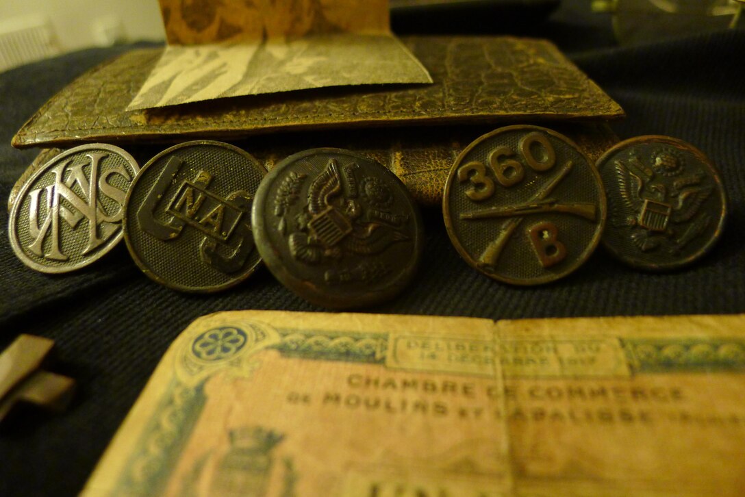 Close-up of uniform buttons, including U.S. National Army; provisional one-franc note from local French chamber of commerce in foreground.