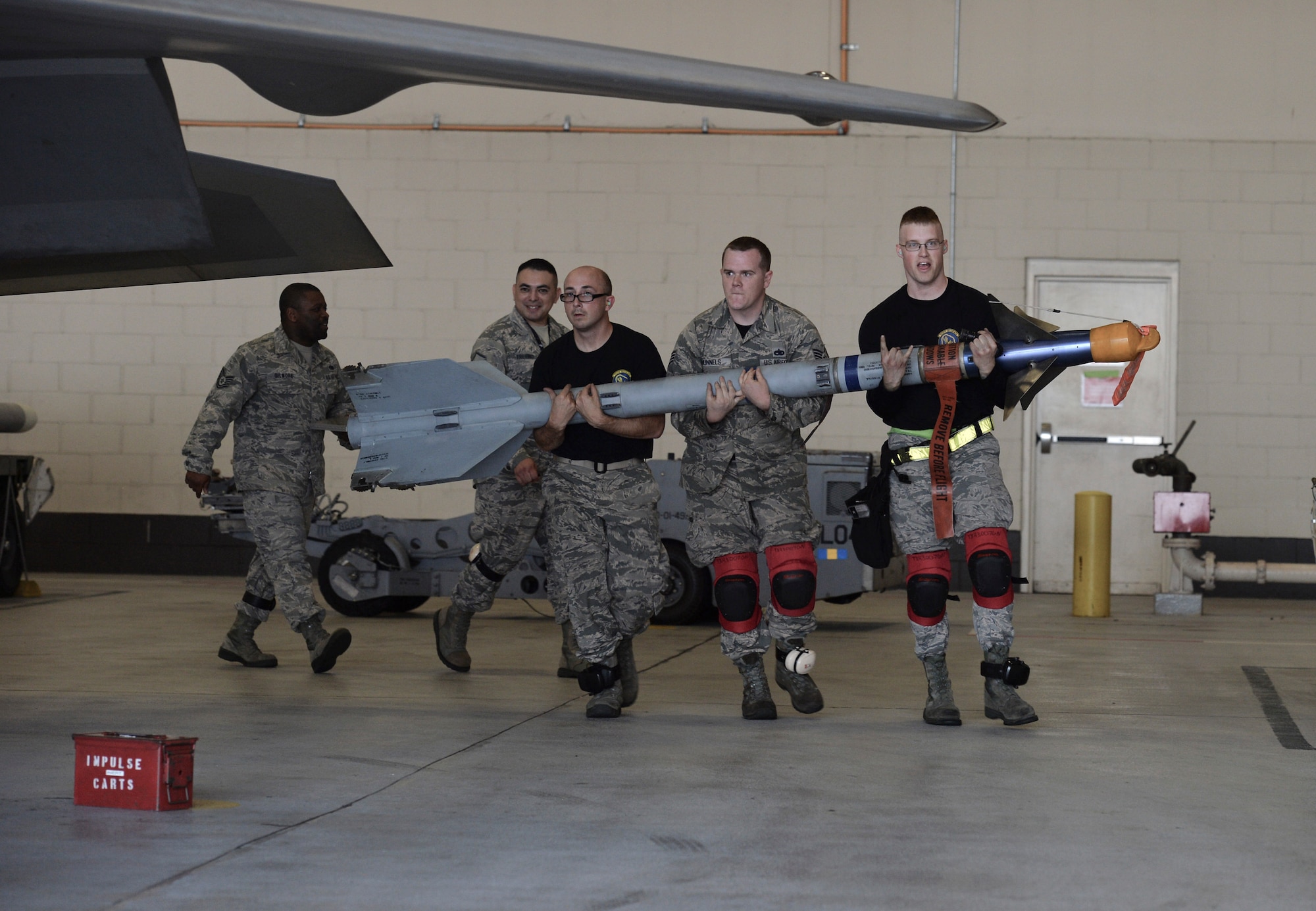 U.S. Air Force Staff Sgts. Nicholas Williams (left), Matthew Runnels (middle), and Nicholas Kipp (right), 43rd Aircraft Maintenance load crew, carry a weighted training missile to a side weapons bay on an F-22 Raptor during the 2016 Weapons Load Crew of the Year competition at Tyndall Air Force Base, Fla., Jan. 20, 2017. The trio were named the best weapons load crew of the year for 2016 during the Maintenance Professional of the Year awards ceremony. (U.S. Air Force photo by Tech. Sgt. Javier Cruz/Released) 