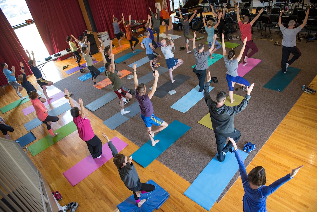 Here, TSgt Sandy Sisk leads members from all different flights in the building in a cheerful and challenging yoga session. TSgt Sisk plays bassoon in the Concert Band, and is also certified as a yoga instructor, who holds regular sessions throughout the month in the squadron. (US Air Force photos/CMSgt Kevin Burns/released)