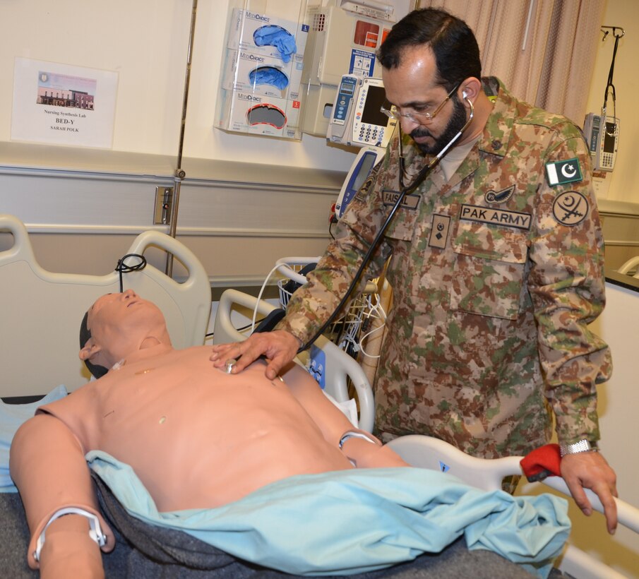 Lt. Col. Faisal Qazi from Pakistan, a participant in the U.S. Central Command Theater Medical Conference, exams a "patient" in the Nurse Synthesis Laboratory during a tour of the Basic Medical Technician Corpsman program at the Medical Education and Training Campus at Joint Base San Antonio-Fort Sam Houston. The patient is a high-tech human-patient, high-fidelity mannequins, or SimMan, used in the BMTC course to help train Navy and Air Force students to become Air Force medical technicians and Navy hospital corpsmen.