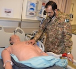 Lt. Col. Faisal Qazi from Pakistan, a participant in the U.S. Central Command Theater Medical Conference, exams a "patient" in the Nurse Synthesis Laboratory during a tour of the Basic Medical Technician Corpsman program at the Medical Education and Training Campus at Joint Base San Antonio-Fort Sam Houston. The patient is a high-tech human-patient, high-fidelity mannequins, or SimMan, used in the BMTC course to help train Navy and Air Force students to become Air Force medical technicians and Navy hospital corpsmen.