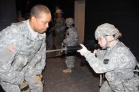 Sgt. 1st Class Peter Vines, acting first sergeant for the U.S. Army Reserve’s 318th Press Camp Headquarters, helps Staff Sgt. Carrie Castillo with proper weapon placement prior to conducting a dismounted patrol lane March 20 at the New Jersey National Guard’s Joint Training and Training Development Center on Joint Base McGuire-Dix-Lakehurst, New Jersey.  The training is part of the unit’s annual training which includes refresher courses on basic Soldier skills.