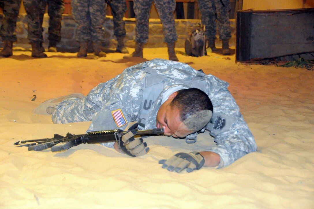 Sgt. 1st Class Peter Vines, acting first sergeant for the U.S. Army Reserve’s 318th Press Camp Headquarters, demonstrates proper low-crawl techniques March 20 before Soldiers go through the desert lane at the New Jersey National Guard’s Joint Training and Training Development Center on Joint Base McGuire-Dix-Lakehurst, New Jersey.  The training is part of the unit’s annual training which includes refresher courses on basic Soldier skills.