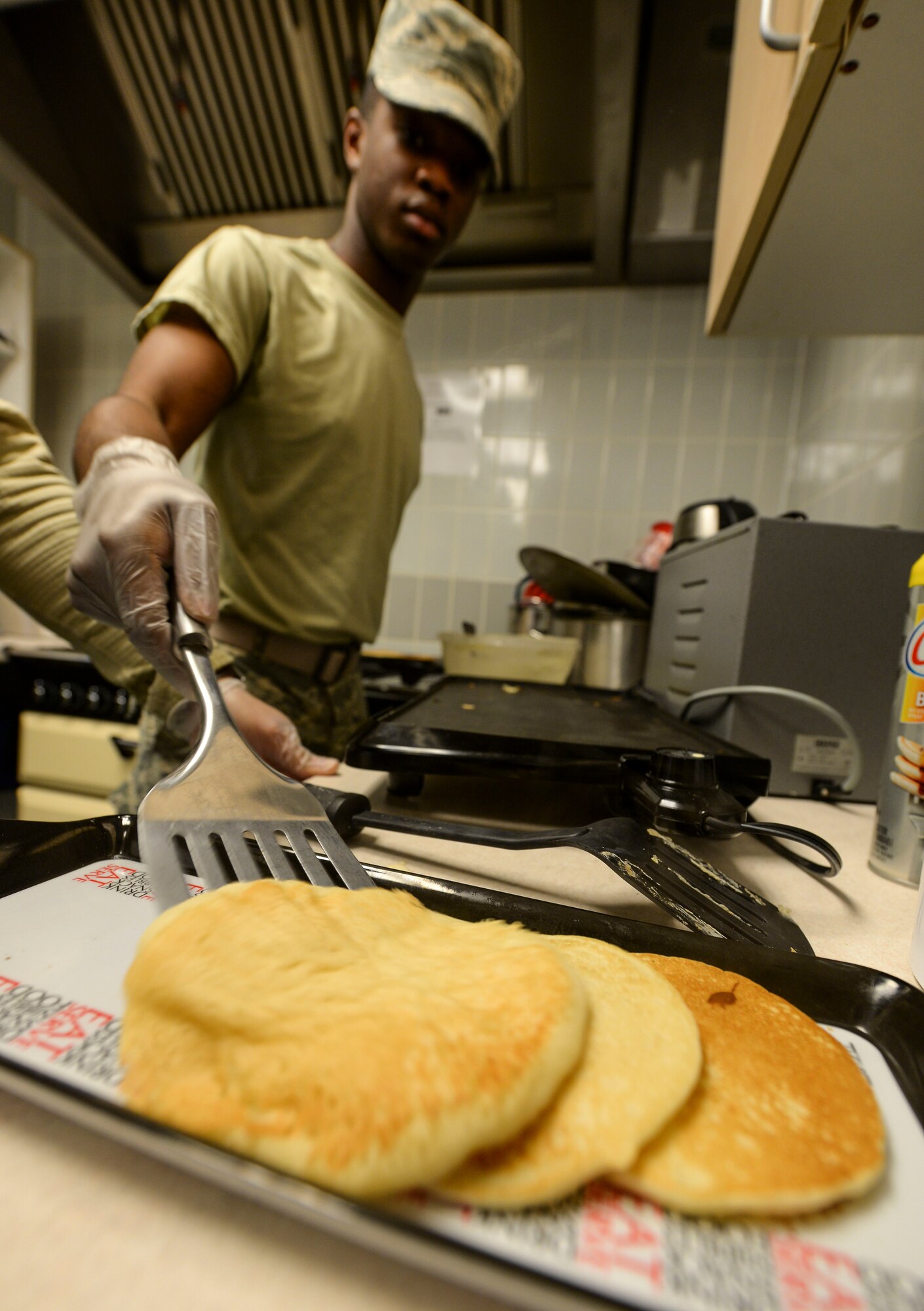 U.S. Air Force Airman 1st Class DeSean Gunter, 100th Communications Squadron client systems technician, prepares pancakes in the base chapel March 21, 2017, on RAF Mildenhall, England. Volunteers and members of the Airmen Committed to Excellence council joined together to make breakfast for junior enlisted personnel across base. (U.S. Air Force photo by Staff Sgt. Micaiah Anthony)