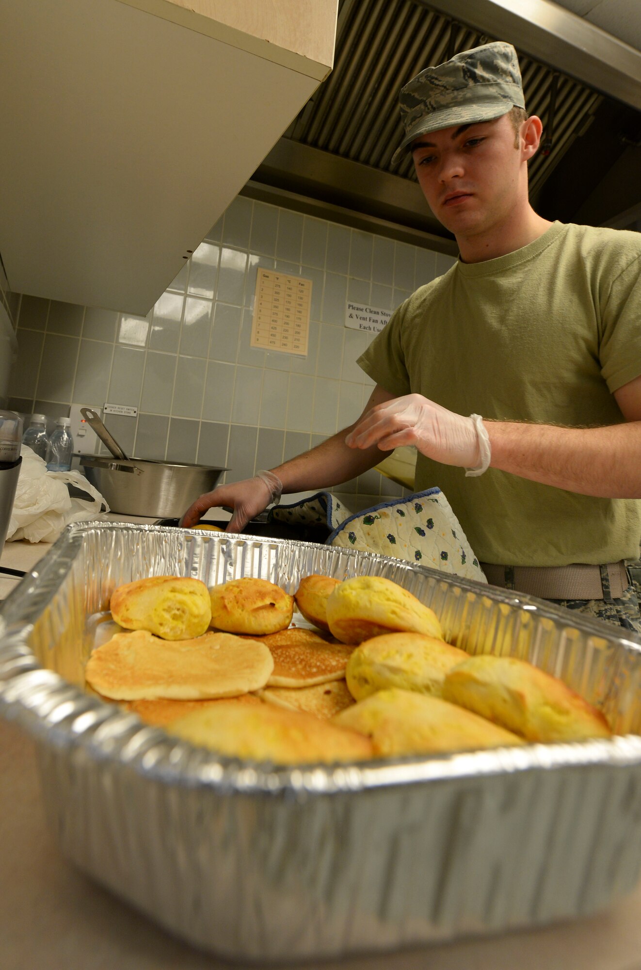 U.S. Air Force Airman 1st Class Austin Gembeck, 100th Maintenance Squadron aerospace ground equipment apprentice, places biscuits in the base chapel March 21, 2017, on RAF Mildenhall, England. Airmen in the ranks from airman basic to senior airman were invited to the base chapel to enjoy a free breakfast, compliments of the Airmen Committed to Excellence council. (U.S. Air Force photo by Staff Sgt. Micaiah Anthony)