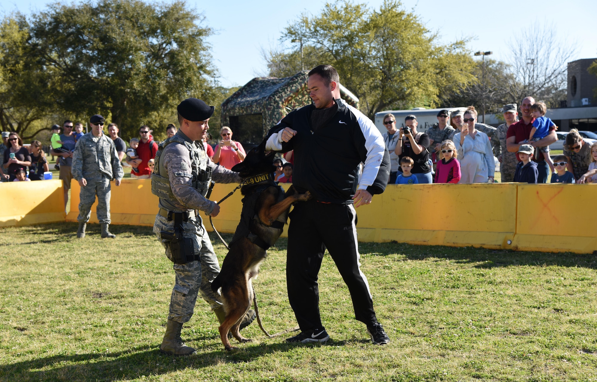 Staff Sgt. Matthew Ratchford and Senior Airmen Timothy Poissant, 81st Security Forces Squadron military working dog handlers, and Toki, 81st SFS military working dog, conduct a MWD demonstration during Operation Hero March 18, 2017, on Keesler Air Force Base, Miss. The activities at the event were to help children better understand what their parents do when they deploy. (U.S. Air Force photo by Kemberly Groue)