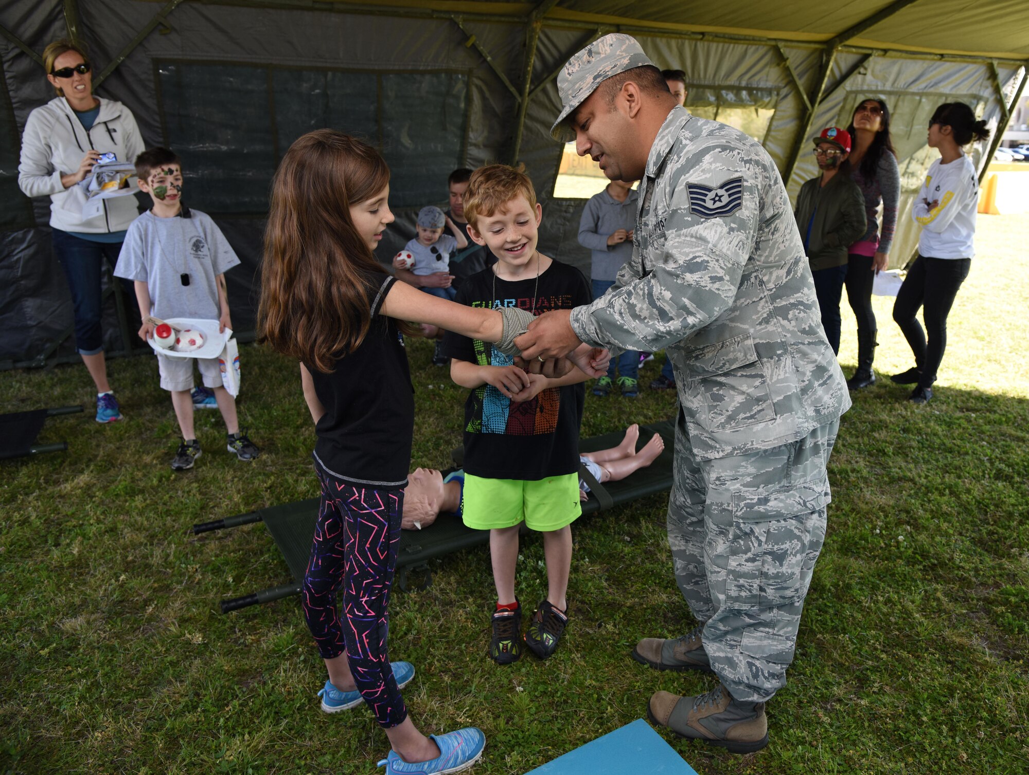 Tech. Sgt. Oscar Rodriguez, 81st Medical Support Squadron command support staff NCO in charge, demonstrates how to apply a bandage to Keesler families during Operation Hero March 18, 2017, on Keesler Air Force Base, Miss. The activities at the event were designed to help children better understand what their parents do when they deploy. (U.S. Air Force photo by Kemberly Groue)