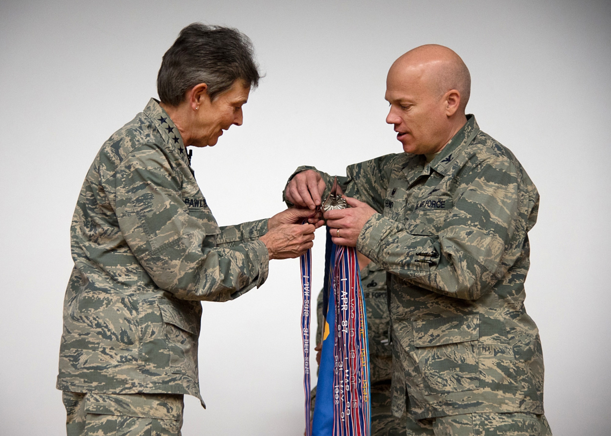 Gen. Ellen M. Pawlikowski, Air Force Materiel Command commander, and Col. Roman L. Hund, 66th Air Base Group commander, place the Air Force Outstanding Unit Award streamer to the 66 ABG unit guidon following an all call at the base theater March 17. The 66 ABG was awarded the outstanding unit award for exceptional meritorious service for calendar year 2015. (U.S. Air Force photo by Mark Herlihy)