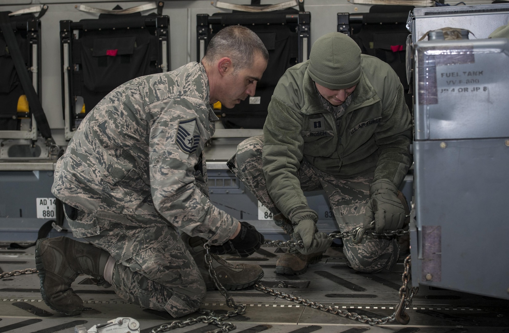 (From left) Master Sgt. Frank Lopez, 5th Logistics Readiness Squadron small air terminal section chief, and Capt. Nicholas Bosch, 5th LRS deployment distributions flight commander, secure cargo onto a C-17 Globemaster III at Minot Air Force Base, N.D., March 3, 2017. The mass deployment included more than 400 deployers and 290,000 pounds of cargo. (U.S. Air Force photo/Airman 1st Class Jonathan McElderry)