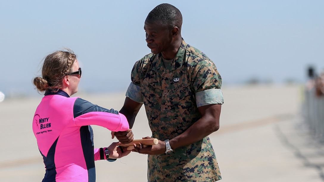 Hanna Albrecht, a member of the Misty Blues All Woman Skydiving Team, passes off a baton to Sgt. Maj. Delvin Smythe, Marine Corps Air Station Yuma Sergeant Major, during the 2017 Yuma Airshow at MCAS Yuma, Ariz., Saturday, March 18, 2017. The airshow served as an opportunity for MCAS Yuma to thank the local community for their continued support.