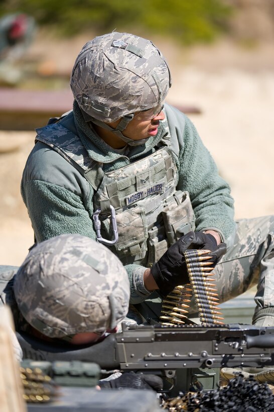 Senior Airman Norman Mosby-Hauer holds a belt containing rounds of 7.62mm ammunition for an M-240B medium machine gun being fired by Airman 1st Class William Young March 9, 2017, at Range 7 on Joint Base McGuire-Dix-Lakehurst, N.J. Both Mosby-Hauer and Young are response force members assigned to 436th Security Forces Squadron, Dover Air Force Base, Del., who traveled to JB MDL to fire the M-240B for quarterly training. (U.S. Air Force photo by Roland Balik)