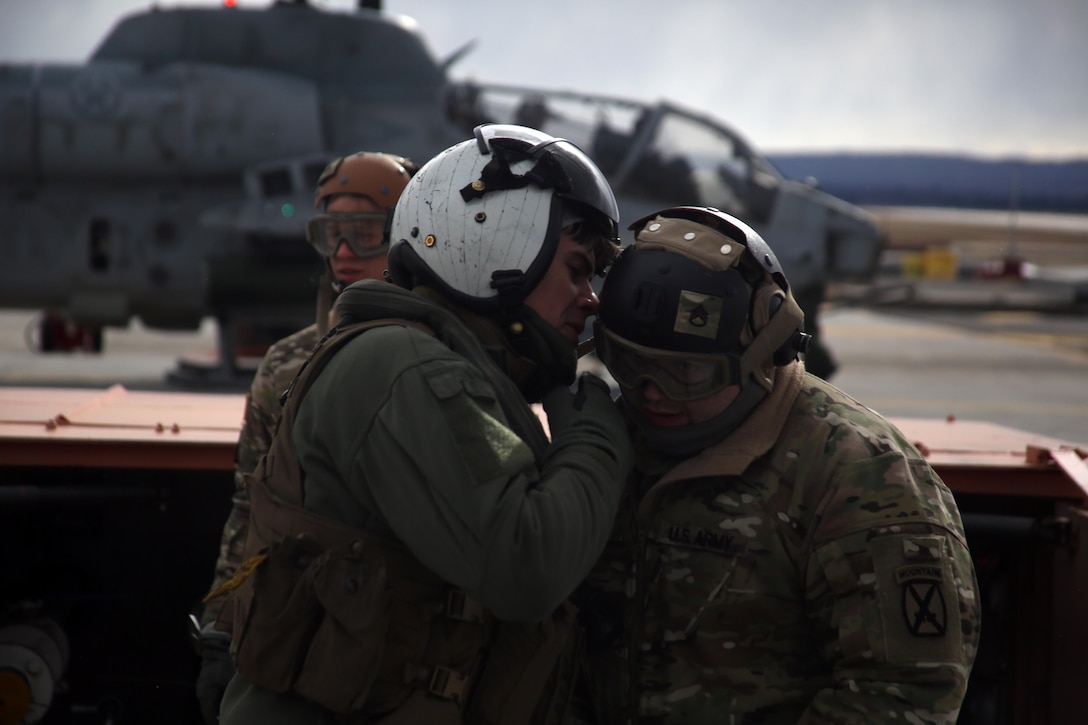 Cpl. Justin Martin talks to a soldier over the loud whir of propellers during cold weather operations aboard Fort Drum, N.Y., March 10, 2017. The training, which began March 8, involves Marines with Marine Light Attack Helicopter Squadron 269, Marine Aircraft Group 29, 2nd Marine Aircraft Wing, along with other various units across the Department of Defense. The Marines will learn how to deal with the challenges that come with working in cold, and sometimes snowy and icy environments. Martin is a flight line mechanic with HMLA-269. (U.S. Marine Corps photo by Cpl. Mackenzie Gibson/Released) 