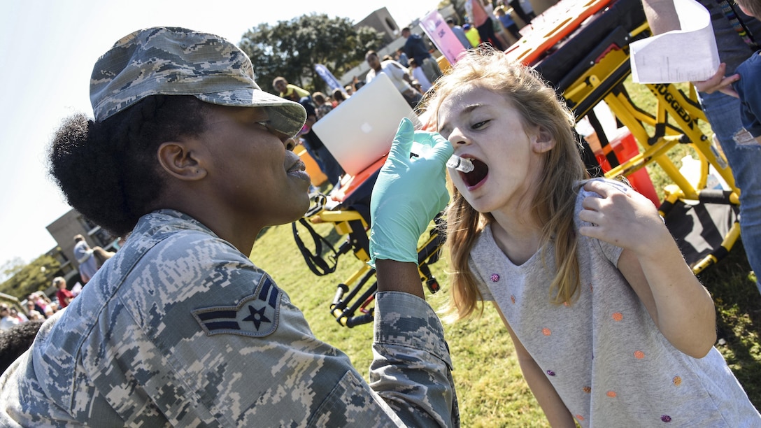 Air Force Airman 1st Class Chante Birdlong administers juice via syringe to a child during an Operation Hero event at Keesler Air Force Base, Miss., March 18, 2017. The event aimed to give military children an idea of what their parents do when they deploy. Air Force photo by Kemberly Groue