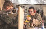 Spc. Daniel Czigler, right, deployed in support of Combined Joint Forces Land Component Command – Operation Inherent Resolve, assigned to 258th Engineer Utilities Detachment, drills into a stand-up desk while Spc. Adam Heath, carpentry and masonry specialist, 258th EUD, holds the desk in place in Baghdad, Iraq, March 6. Czigler is an interior electrician by trade but learned he would be doing a lot of wood work when he arrived.
