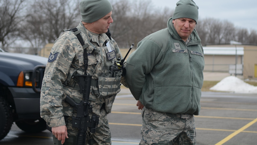 Tech. Sgt. Dan Hammett, 115th Fighter Wing Security Forces Squadron fire team leader, handcuffs and questions Staff Sgt. Christopher Schuster, 115 FW SFS Airman, during the squadron's quarterly capstone exercise on base March 18, 2017. The capstone exercise gave security forces Airmen a chance to train on law enforcement fundamentals, knowledge they need when deployed with active duty units. The training gave drill status guardsmen and the full-time active guard reserve Airmen a chance to work together. (U.S. Air National Guard photo by Staff Sgt. Andrea F. Rhode/released)