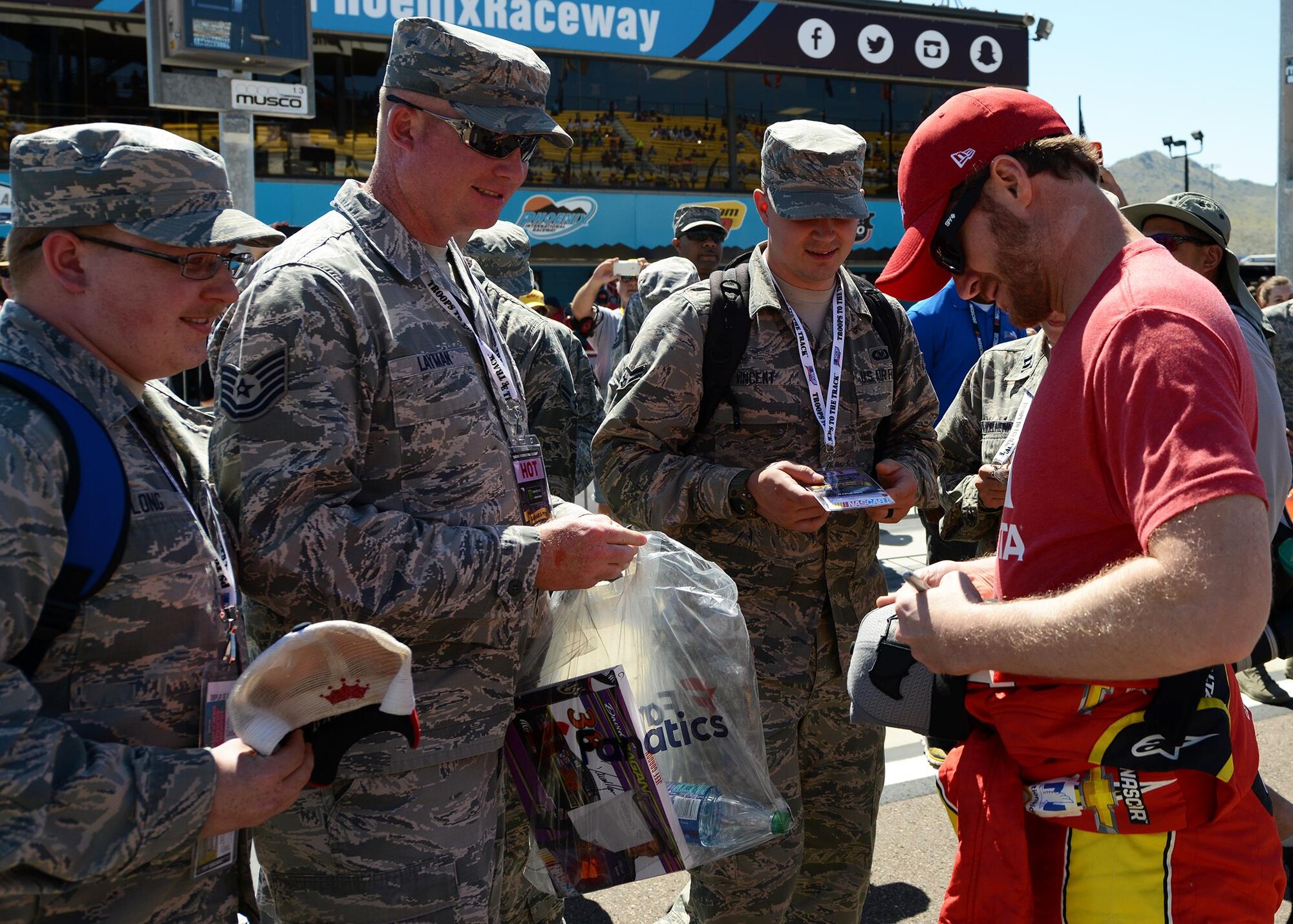 Dale Earnhardt Jr., NASCAR driver, autographs merchandise for Airmen during the introduction of the racers at the Camping World 500 Mar. 19, 2017, at the Phoenix International Raceway, Avondale, Ariz. (U.S. Air Force photo by Airman First Class Alexander Cook)