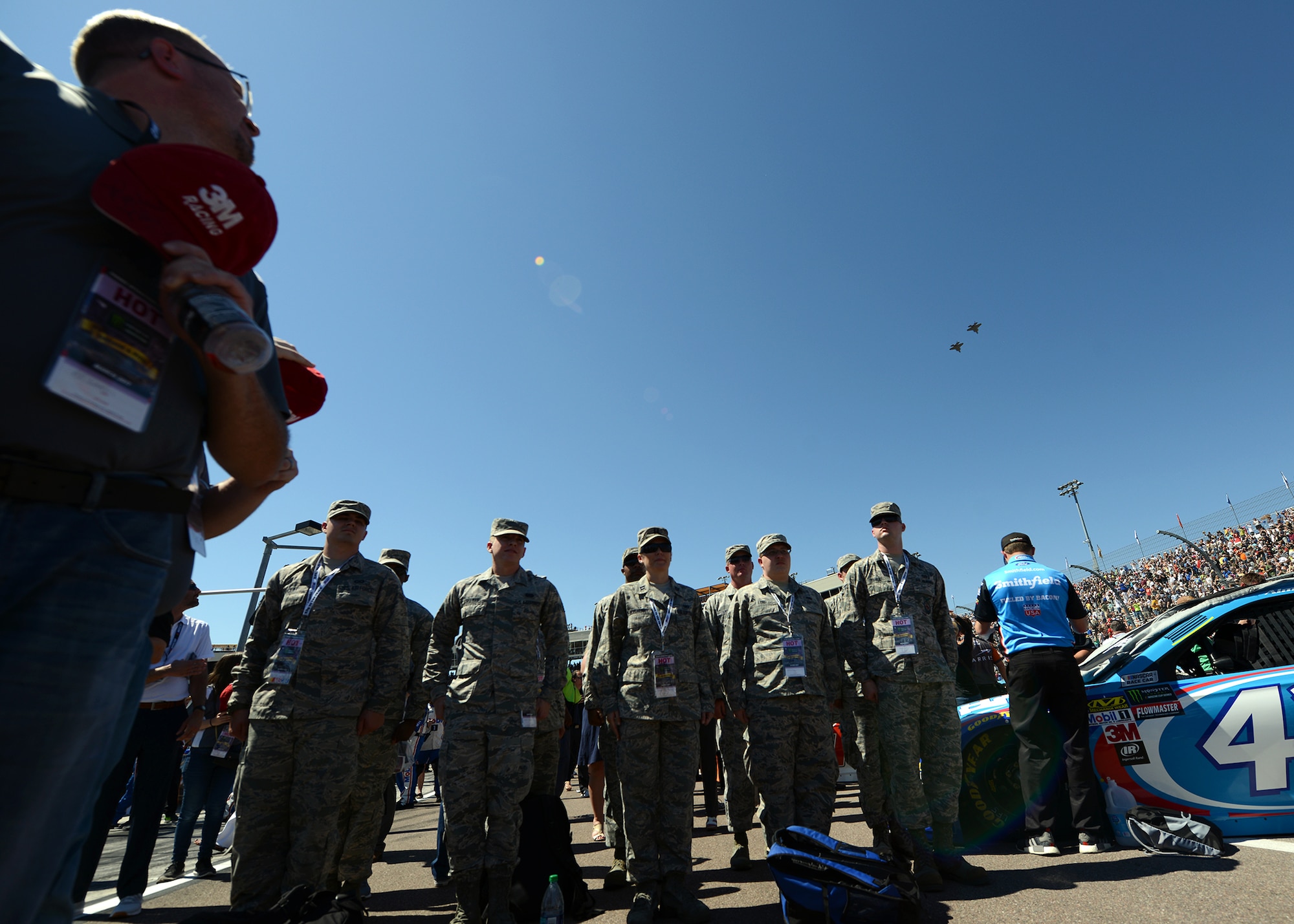 Airmen from Luke Air Force Base stand at attention while two F-35s from the 62nd Fighter Squadron perform a flyover during the opening ceremony of the Camping World 500 Mar. 19, 2017, at the Phoenix International Raceway, Avondale, Ariz. (U.S. Air Force photo by Airman First Class Alexander Cook)  