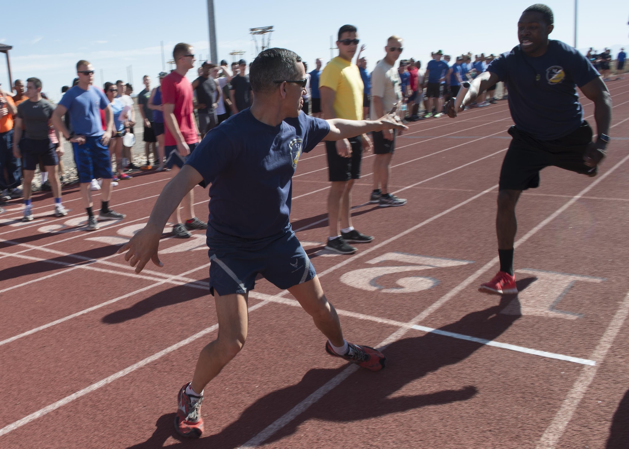 An Airman hands off a baton during a one-mile relay during the 49th Wing Sports Day, March 17, 2017 at Holloman Air Force Base, N.M. Sports Day included a number of events, such as basketball, dodgeball, football, and many more. The day ended with a one-mile relay and awards presentation. (U.S. Air Force photo by Senior Airman Emily Kenney)  