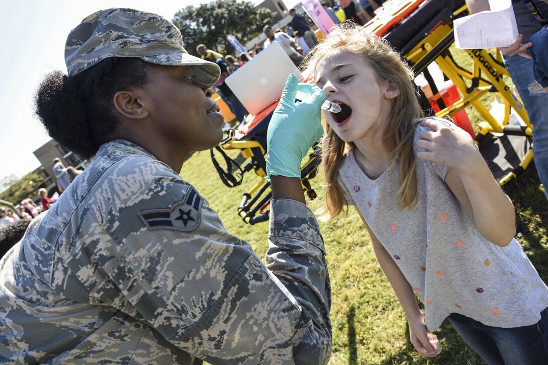 Airman 1st Class Chante Birdlong administers juice via syringe to a child during an Operation Hero event at Keesler Air Force Base, Miss., March 18, 2017. The event aimed to give military children an idea of what their parents do when they deploy. Air Force photo by Kemberly Groue