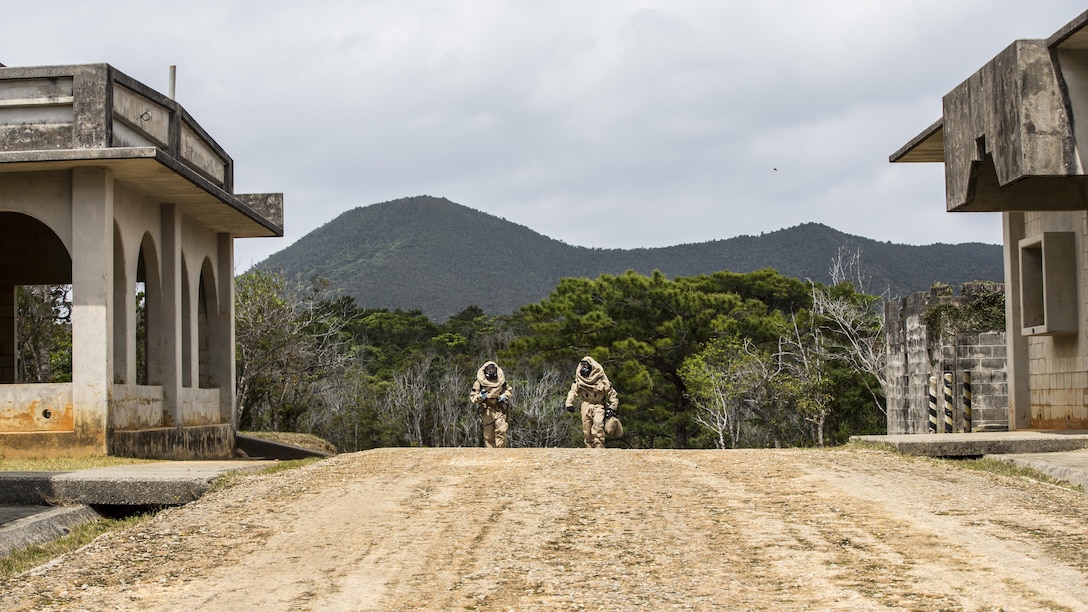 U.S. Marine Corps Cpl. James Dietrich, Sampling Team leader, right, and Lance Cpl. Nickolas Giffen, Sampling Team Member, with Chemical, Biological, Radiological and Nuclear (CBRN) Platoon, G-3, 3d Marine Division, head toward the simulated “hot zone” in modified Level B suits on Combat Town, Okinawa, Japan, March 21, 2017. The CBRN Platoon conducts response drills to enhance the commander’s capabilities by exercising the operability and efficiency of the consequence management set within the 3d Marine Division CBRN response element. (U.S. Marine Corps photo by MCIPAC Combat Camera Lance Cpl.  Jesus McCloud)