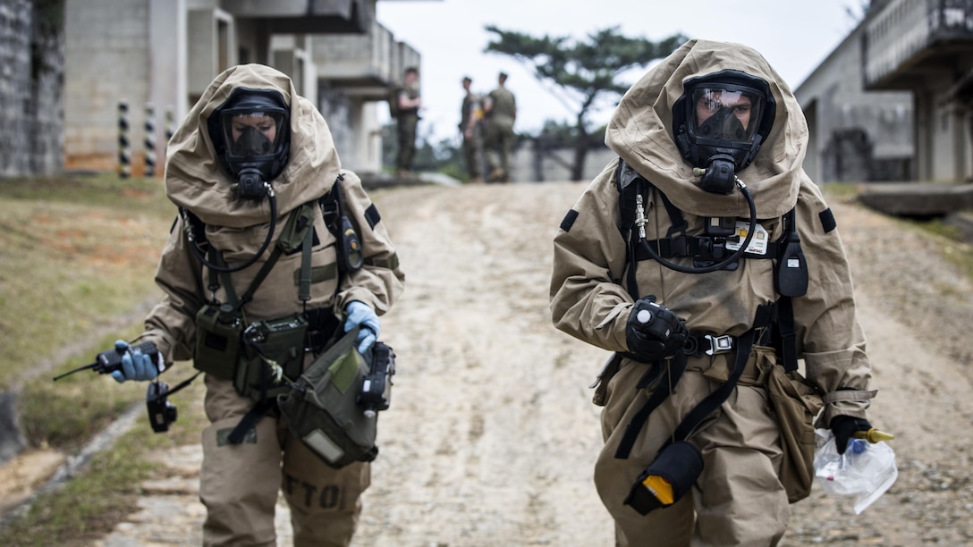 U.S. Marine Corps Lance Cpl. Mellisa Leathery, Recon Team member, left, and Cpl. Joshua Hatfield, Recon Team Leader, with Chemical, Biological, Radiological and Nuclear Platoon, G-3, 3d Marine Division, walk towards the decontamination line after gathering reconnaissance of the simulated CBRN hazard at Combat Town, Okinawa, Japan, March 21, 2017. The CBRN Platoon conducts response drills to enhance the commander’s capabilities by exercising the operability and efficiency of the consequence management set within the 3d Marine Division CBRN response element.