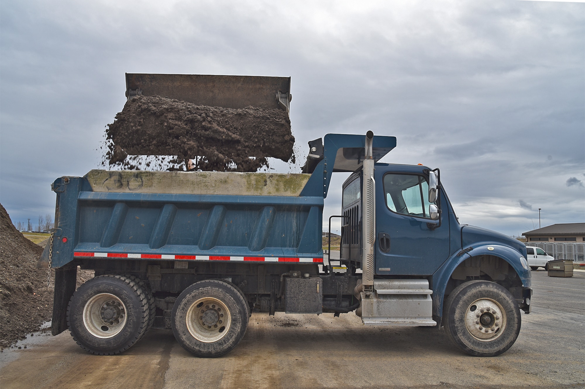 The 92nd Civil Engineer Squadron pavement and construction shop uses a loader to load a dump truck with dirt Mar. 15, 2017, at Fairchild Air Force Base, Washington. The loader and dump truck are two of more than 100 different pieces of machinery utilized by the shop. (U.S. Air Force photo/Senior Airman Mackenzie Richardson) 