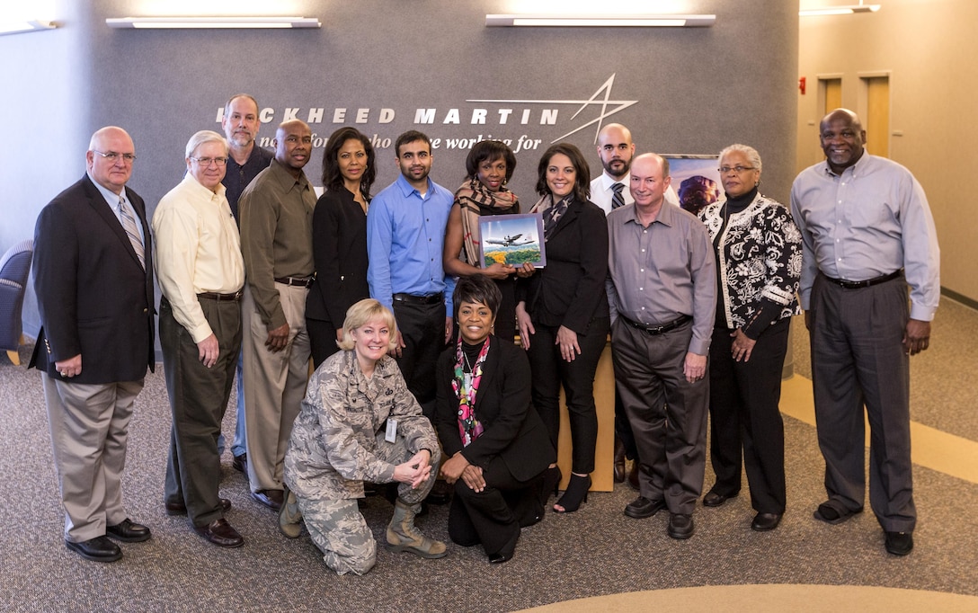 Anthony Zompetti, the Air Force's director of Development & Production, C-130 Hercules Division, presented the Defense Contract Management Agency Lockheed Martin Marietta team with a token of appreciation in February for saving the government $680 million on its $5.3 billion contract for C-130 Hercules aircraft. Zompetti stands with DCMA employees Barry Lubrant, David Wolfinge, Richard Bolden, Priscilla Driscoll, Miral Patel, Marguerite Antoine, Sarah Sullivan, Isaiah Wilcox, Phillip Beckwith, LaNorma Shelton-Thomas and Bernard Latimore. Kneeling are Air Force Col. Sheri Bennington, DCMA Lockheed Martin Marietta commander, and Myra Tate, deputy commander. Team members Todd Landeche, Marieco Myart, Dexter Harper, Rachel Buckner and Rocky Miller are not shown. (DCMA photo courtesy of DCMA Lockheed Martin Marietta) 