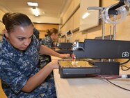 Machinery Repairman 2nd Class Lisa Petyak watches the 3-Dimensional (3-D) printer inside SERMC's Fabrication Laboratory, or Fab Lab. The Fab Lab hopes to spark creativity and problem-solving skills for Sailors assigned to SERMC.